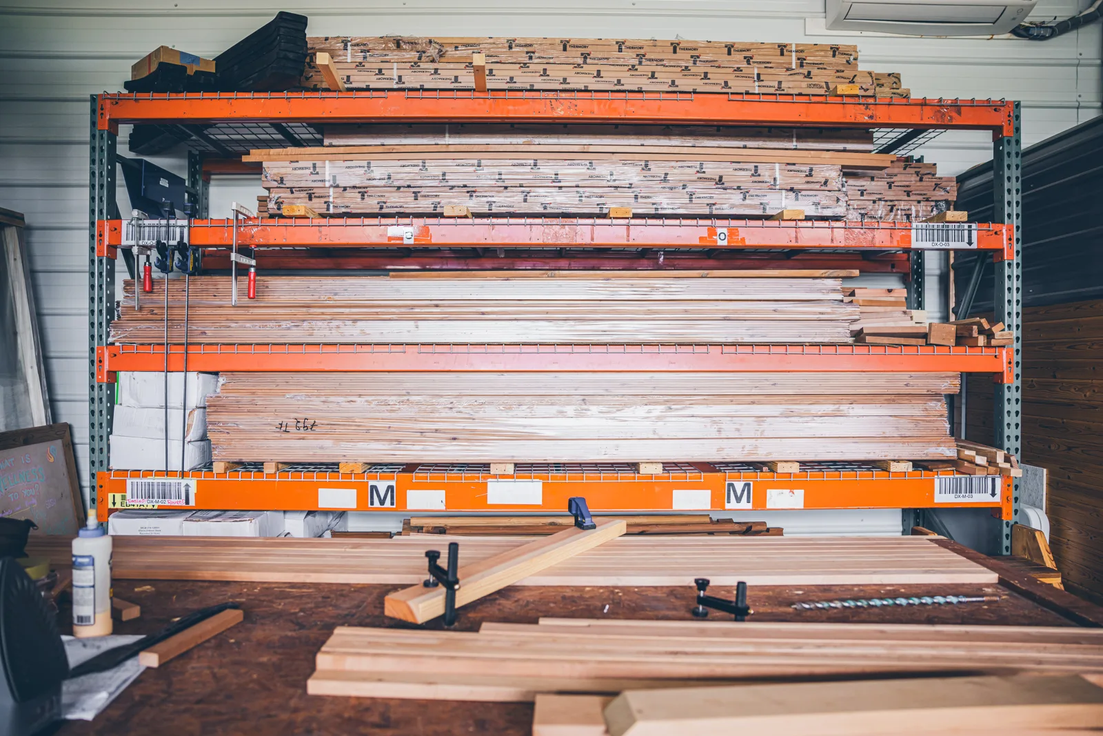 A cantilever rack loaded with tiers of stacked lumber boards in the shop
