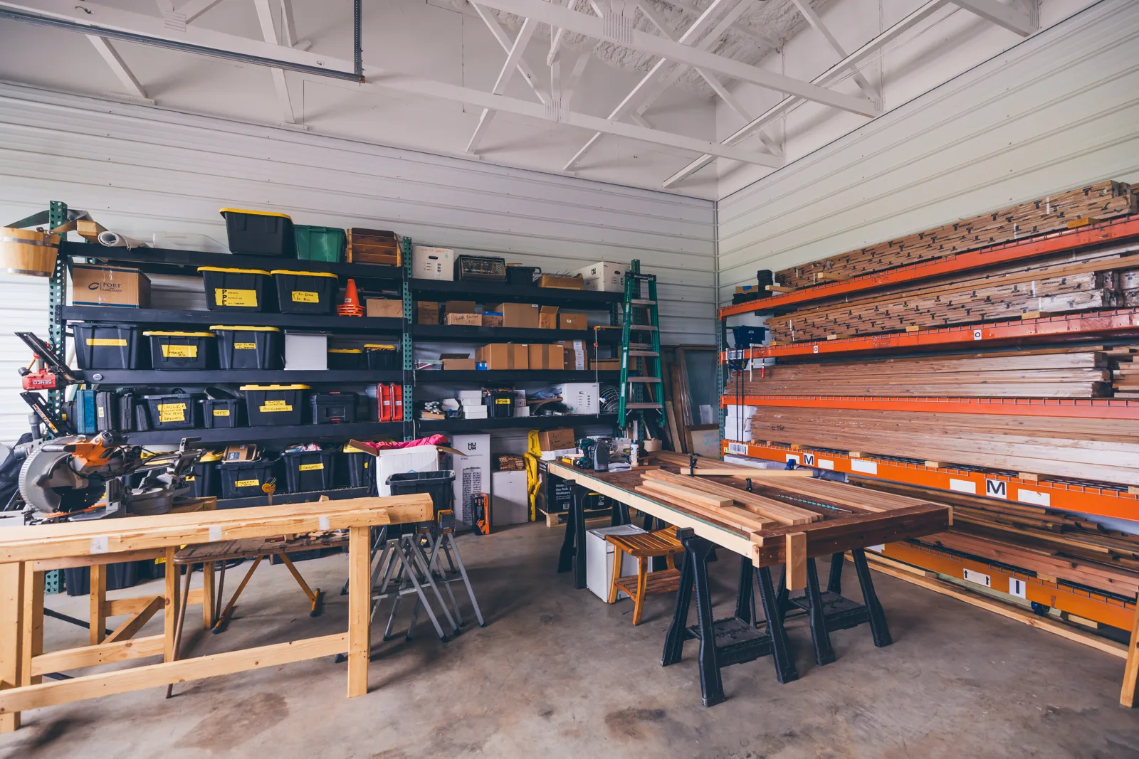 Workshop floor with workbenches, tool shelving and racks of stacked lumber