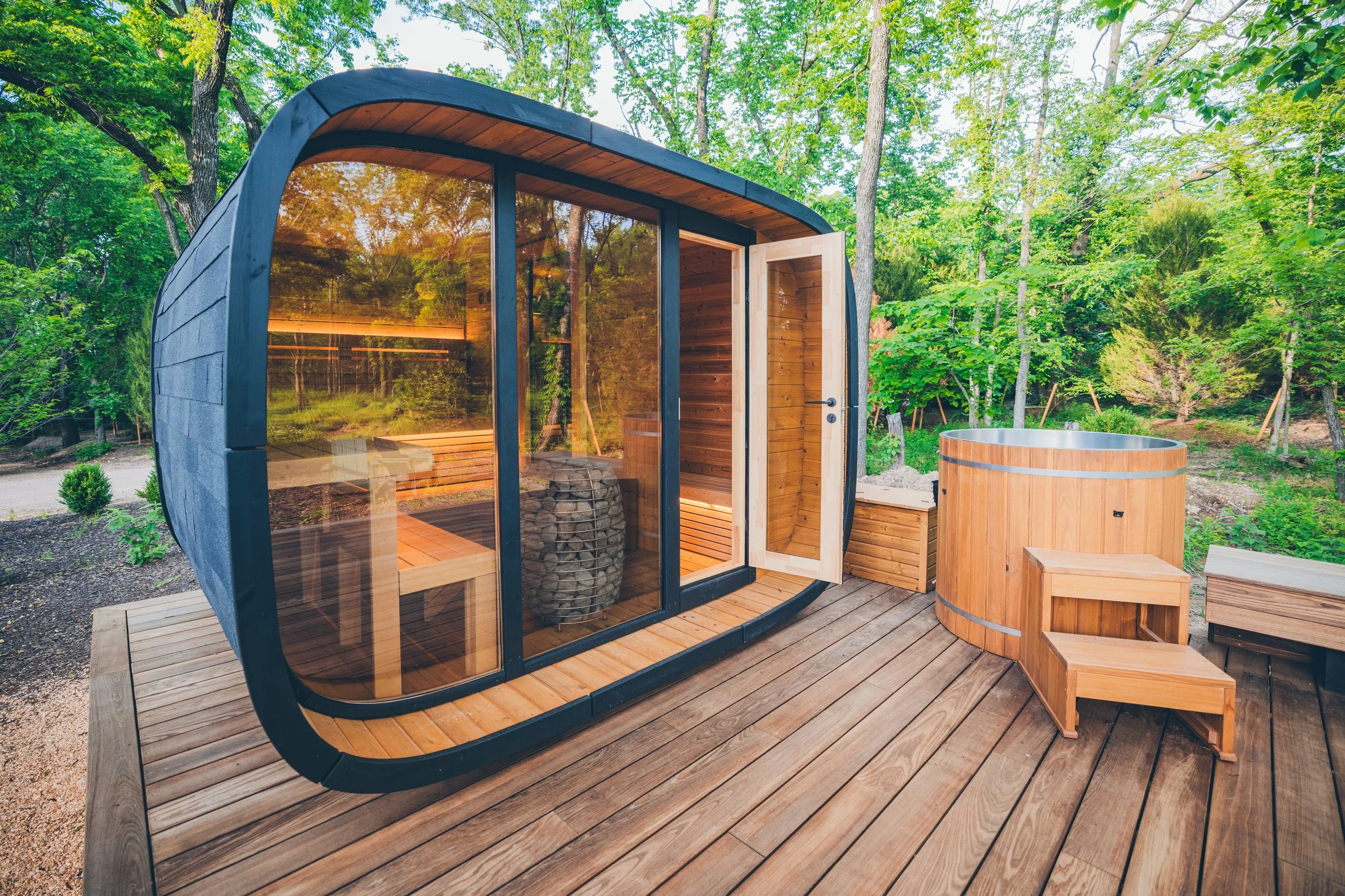 Modern outdoor glass-walled Chillfire sauna on a deck beside a wooden cold plunge tub