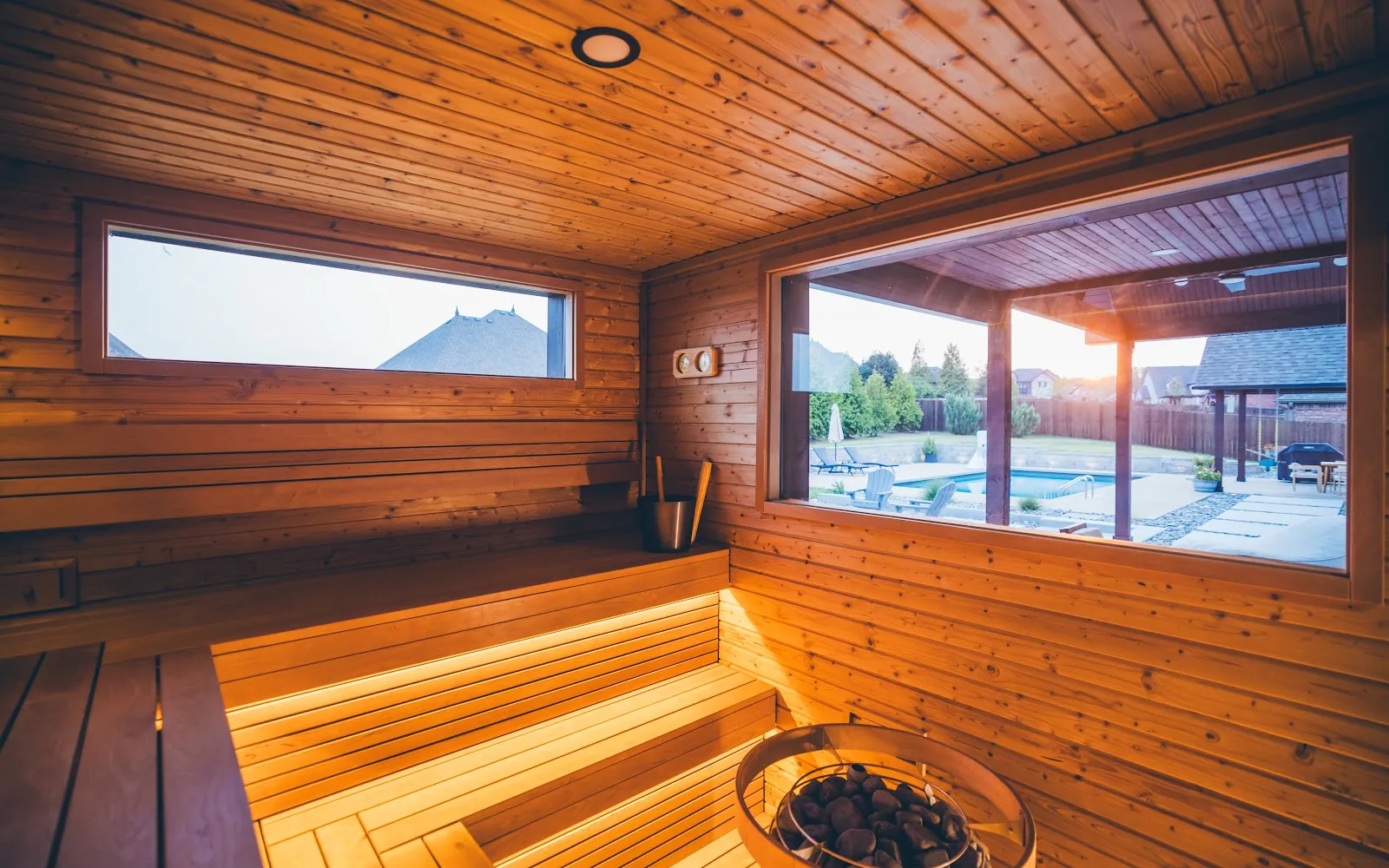 Sauna interior looking out through a large window to a pool and patio.