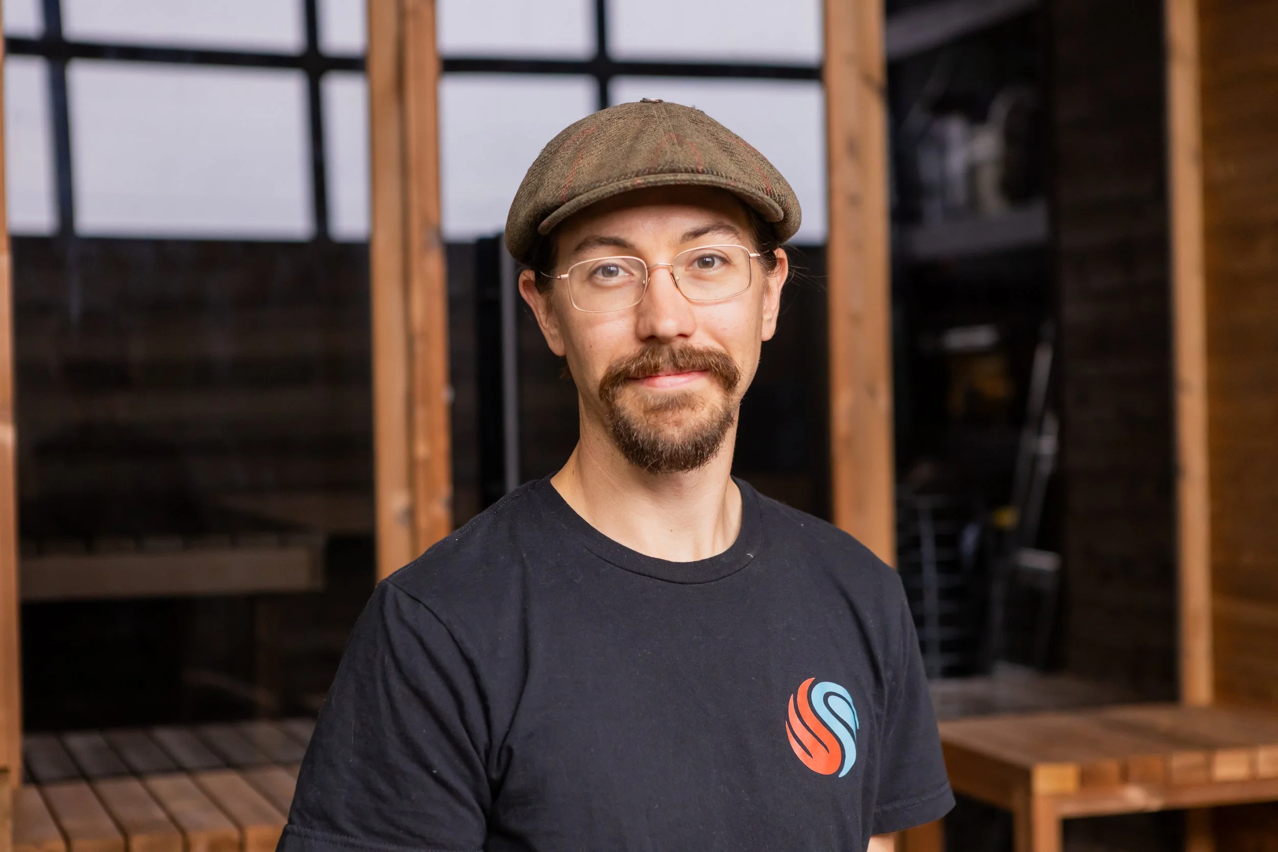 Chillfire Sauna Company team member standing indoors by a wooden sauna structure, showcasing our hands-on craftsmanship and custom sauna building process.